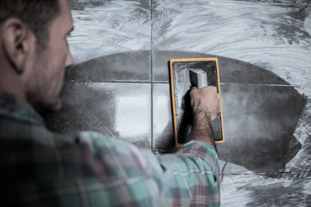 A mason cleans stained tiles with a sponge.