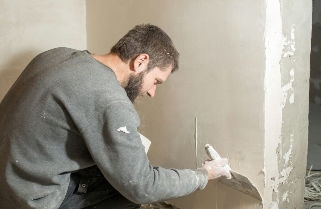 a male plasterer plasters a concrete wall with a spatula.